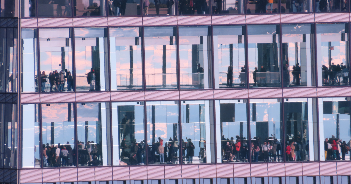 Visitors visible through the glass facade of Summit One Vanderbilt, viewed from the Empire State Building.